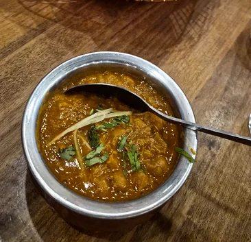 Chole garnished with ginger and coriander in a steel bowl