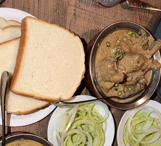 Cream chicken in a pale creamy gravy with green chillies, served with white bread slices and onion rings in mint chutney