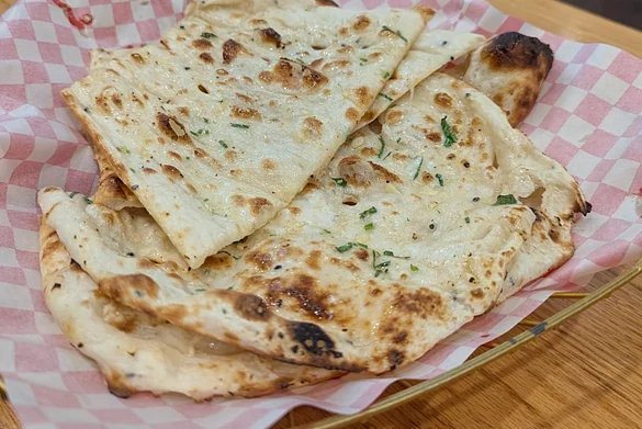 Naan brushed with garlic and coriander in a checkered paper-lined basket