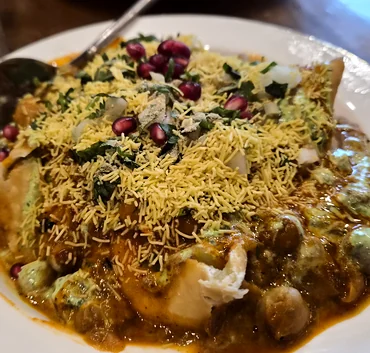 Chaat with sev and pomegranate seeds on a white plate