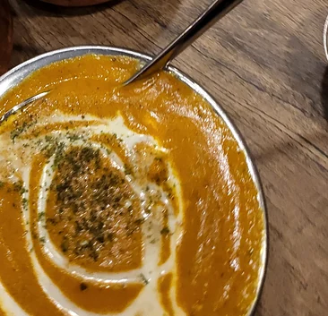 Creamy orange curries with a cream swirl and dried fenugreek in steel bowls