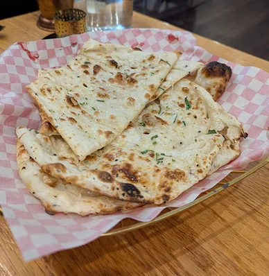 Naan brushed with garlic and coriander in a checkered paper-lined basket