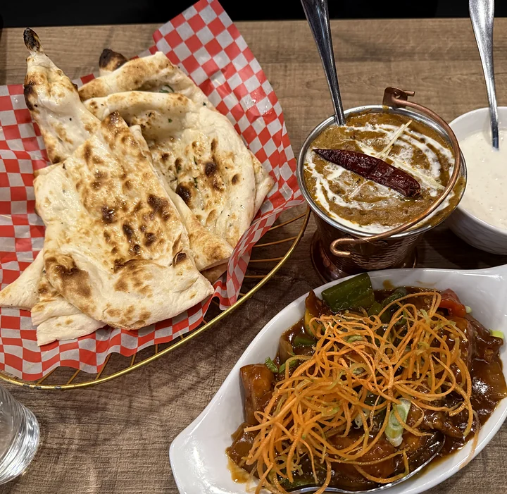 Butter naan in a checkered basket with dal makhani and raita