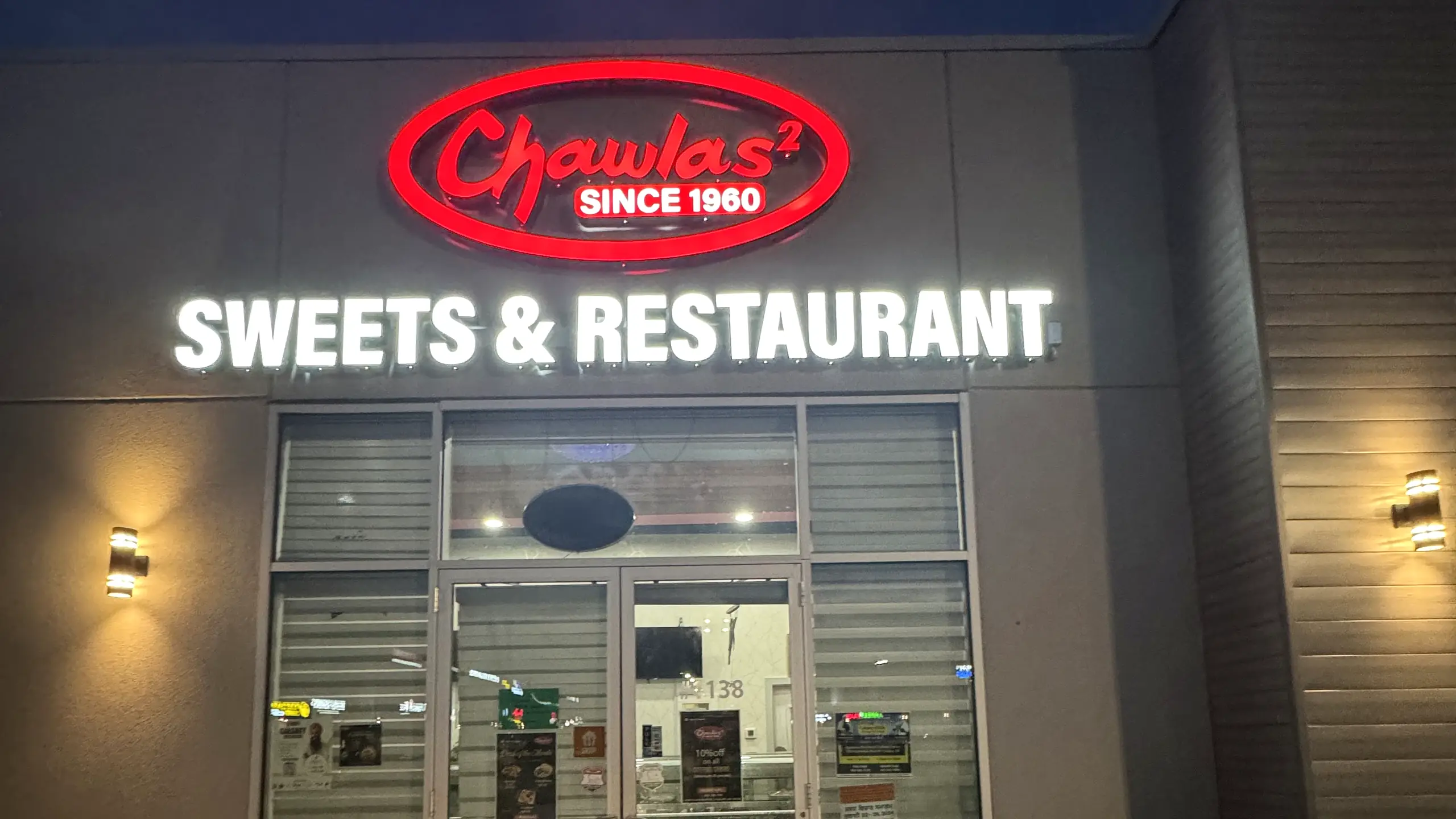 Chawlas² Sweets & Restaurant storefront at night with its lit red Chawlas² sign