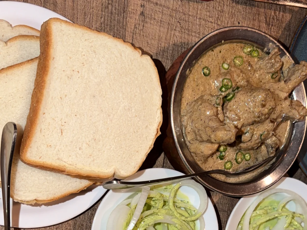 Cream chicken in a pale creamy gravy with green chillies, served with white bread slices and onion rings in mint chutney